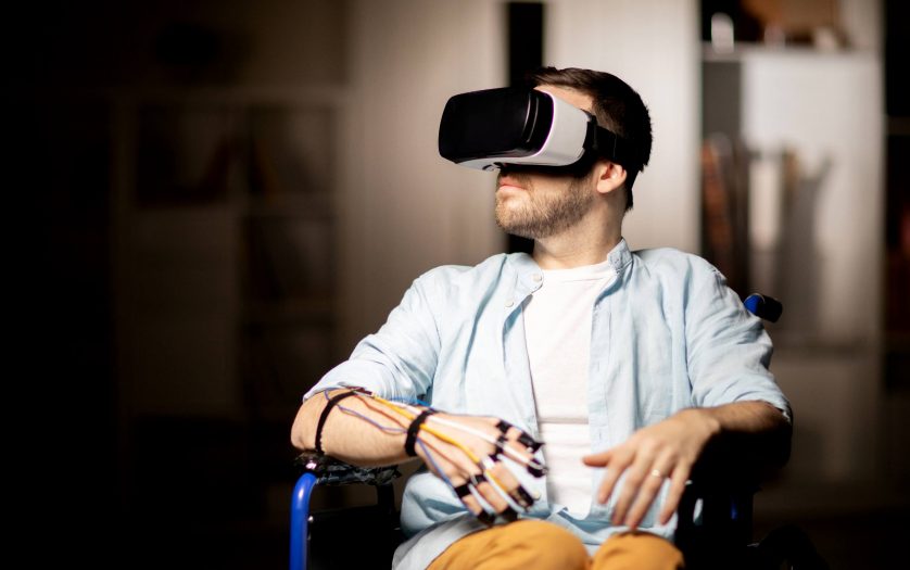 A man in a wheelchair using a VR headset and adaptive head controls