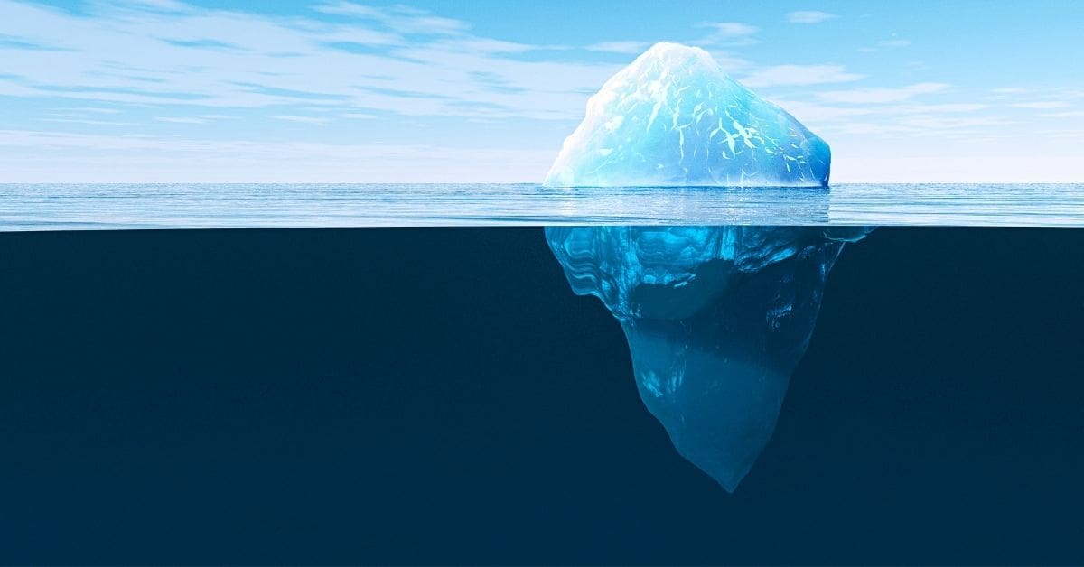 Iceberg floating in ocean with visible underwater portion below waterline, illustrating hidden depths and submerged structure beneath surface